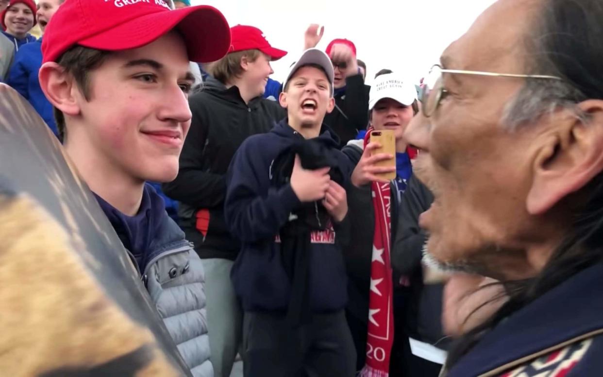 Nicholas Sandmann, 16, a student from Covington Catholic High School stands in front of Native American activist Nathan Phillips in Washington DC - REUTERS