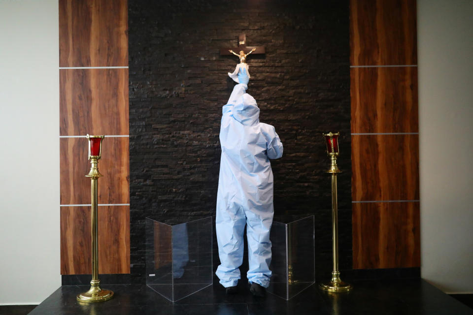 An employee wearing protective clothing disinfects a crucifix at Funeral Gayosso, as the outbreak of the coronavirus disease (COVID-19) continues in Mexico City, Mexico May 11, 2020. Picture taken May 11, 2020. REUTERS/Edgard Garrido