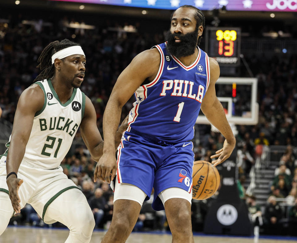 Philadelphia 76ers guard James Harden (1) passes the ball behind his back against Milwaukee Bucks guard Jrue Holiday (21) during the first half of an NBA basketball game Sunday, April 2, 2023, in Milwaukee. (AP Photo/Jeffrey Phelps)