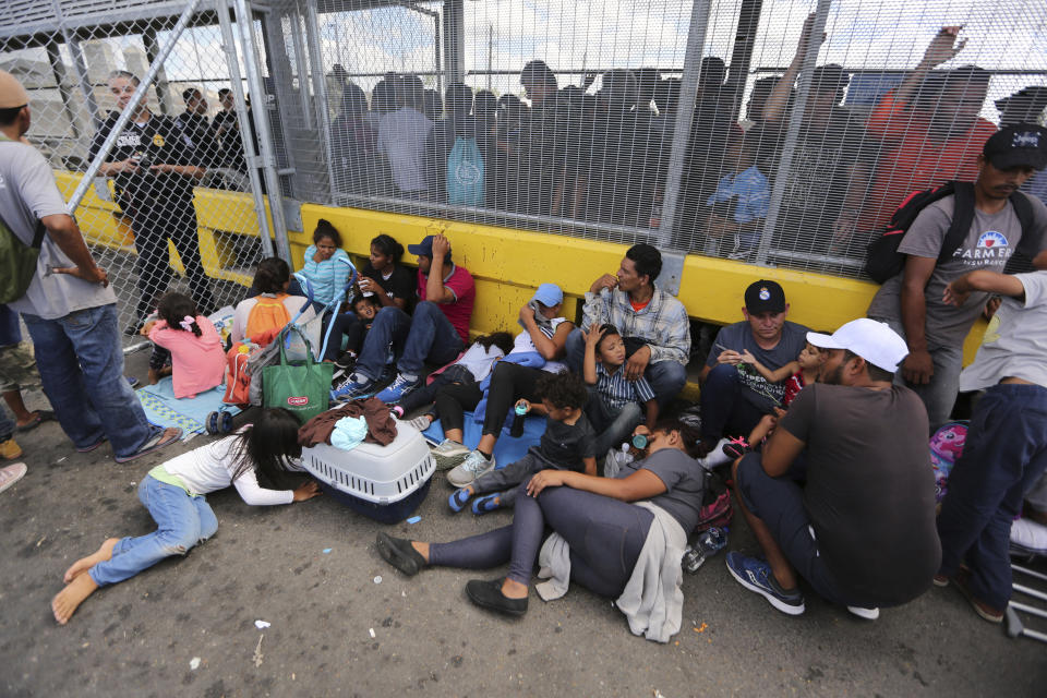 Migrants gather next to the border fence after camping out on the Gateway International Bridge that connects downtown Matamoros, Mexico with Brownsville, Thursday, Oct. 10, 2019. Migrants wanting to request asylum camped out on the international bridge leading from Mexico into Brownsville, Texas, causing a closure of the span. (AP Photo/Fernando Llano)