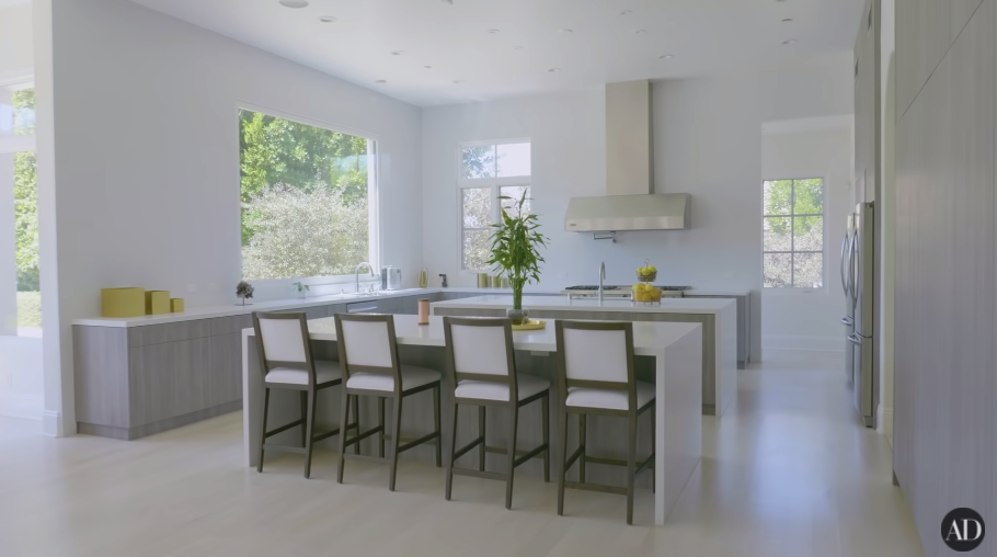A large, very spare white kitchen with an island and large windows