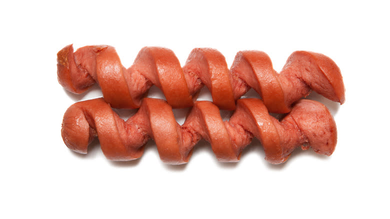 Spiral-cut hot dogs against white