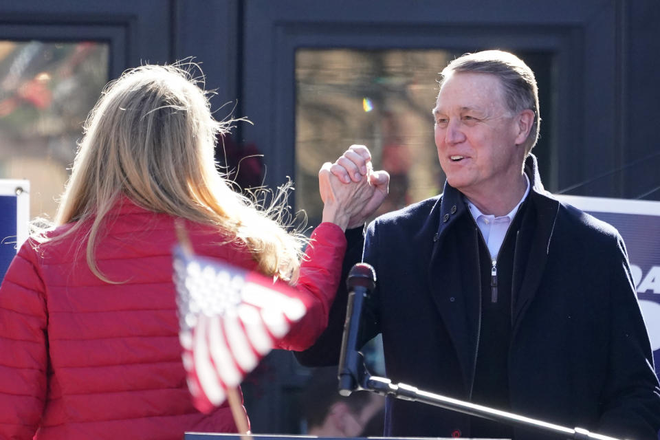 Sen. David Perdue, R-Ga., and Sen. Kelly Loeffler, R-Ga., clasp hands during a campaign rally, Monday Dec. 21, 2020, in Milton, Ga. (AP Photo/John Bazemore)