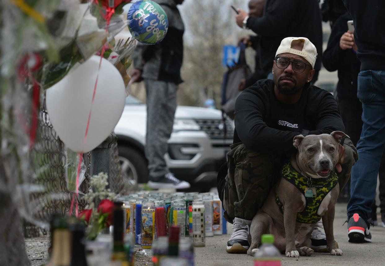 A man looks on holding his dog at a makeshift memorial for hip-hop star DMX outside White Plains hospital in White Plains, New York on April 9. 