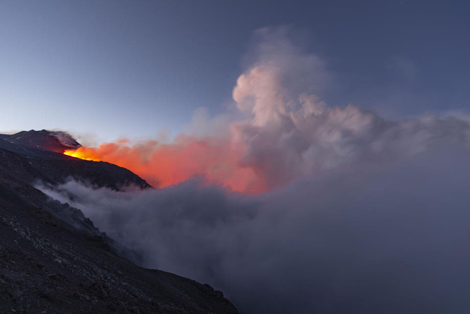 In this photo taken on Thursday, May 30, 2019 and made available Friday, May 31, 2019 Mount Etna volcano spews lava during an eruption. Mount Etna in Sicily has roared back into spectacular volcanic action from Thursday morning, sending up plumes of ash and spewing lava. (AP Photo/Salvatore Allegra)