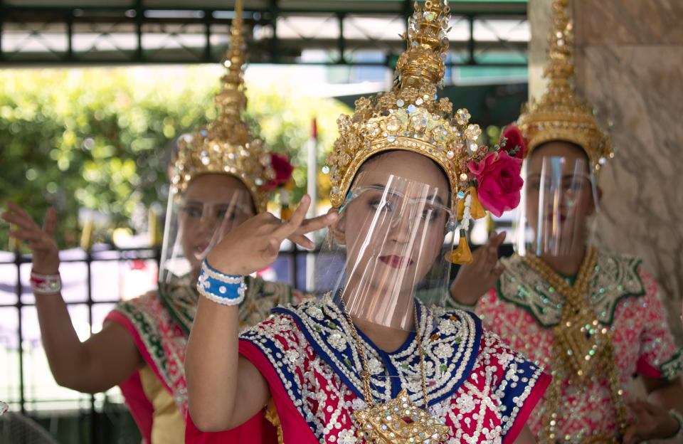 Thai classical dancers wearing face shield to help curb the spread of the coronavirus perform at the Erawan Shrine in Bangkok, Thailand, Thursday, May 28, 2020. Thai government continues to ease restrictions related to running business in capital Bangkok that were imposed weeks ago to combat the spread of COVID-19.(AP Photo/Sakchai Lalit)