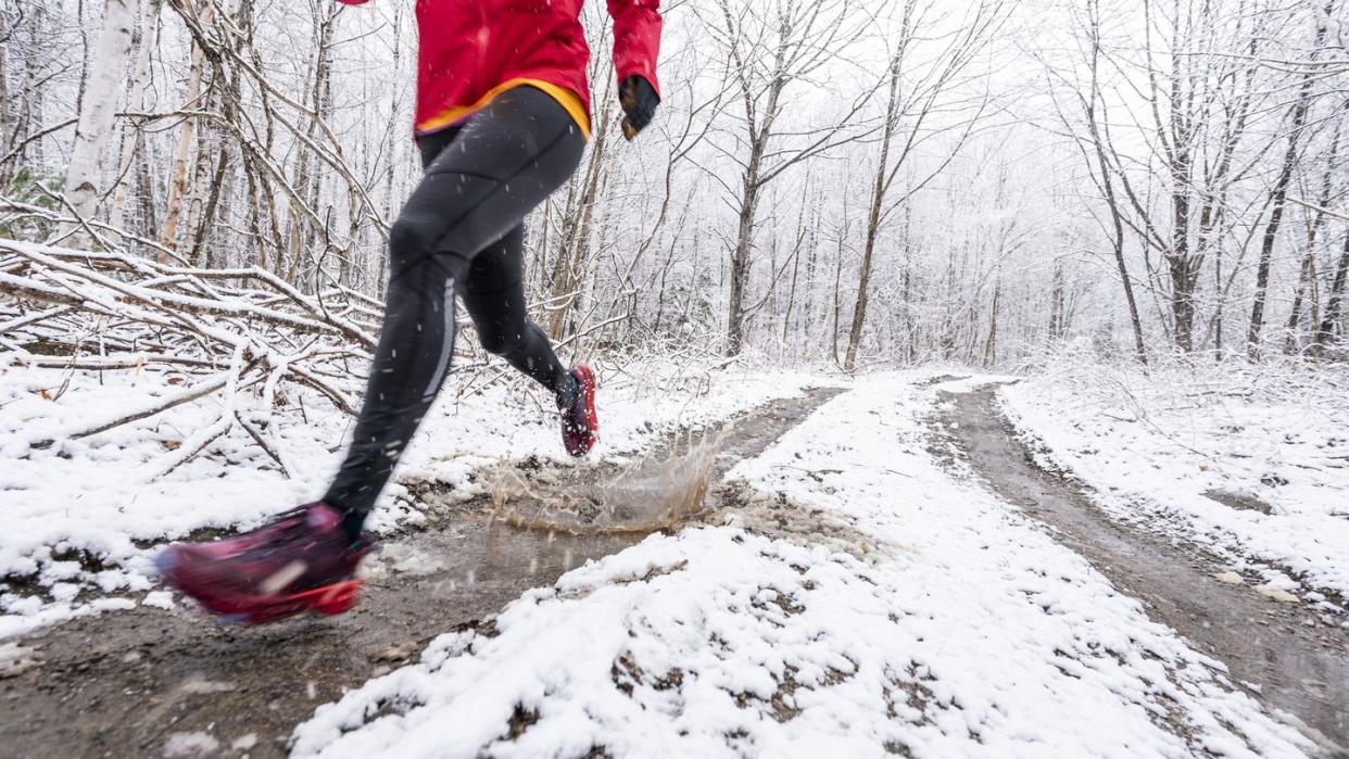 a woman in a red jacket running in mud in winter