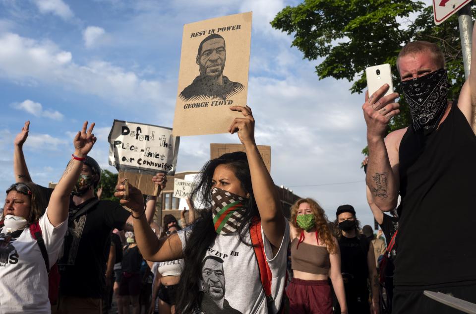 A woman holding a sign and wearing a shirt with George Floyd's face joins other protesters outside the 3rd Police Precinct on May 27, 2020, in Minneapolis, Minnesota. Floyd died in police custody.