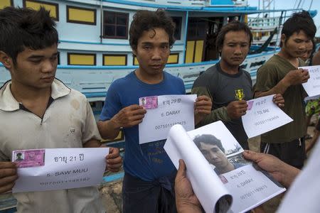 Migrant workers hold up their identity cards as authorities conduct a check at a port in Samut Songkhram province, Thailand, July 1, 2015. REUTERS/Athit Perawongmetha