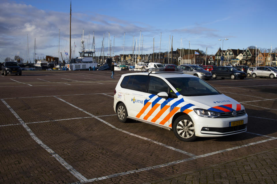 A police vehicle is parked in the harbor near a torched coronavirus testing facility in the Dutch fishing village of Urk, Sunday, Jan. 24, 2021. It was set ablaze Saturday night by rioting youths protesting on the first night of a nation-wide curfew. (AP Photo/Peter Dejong)
