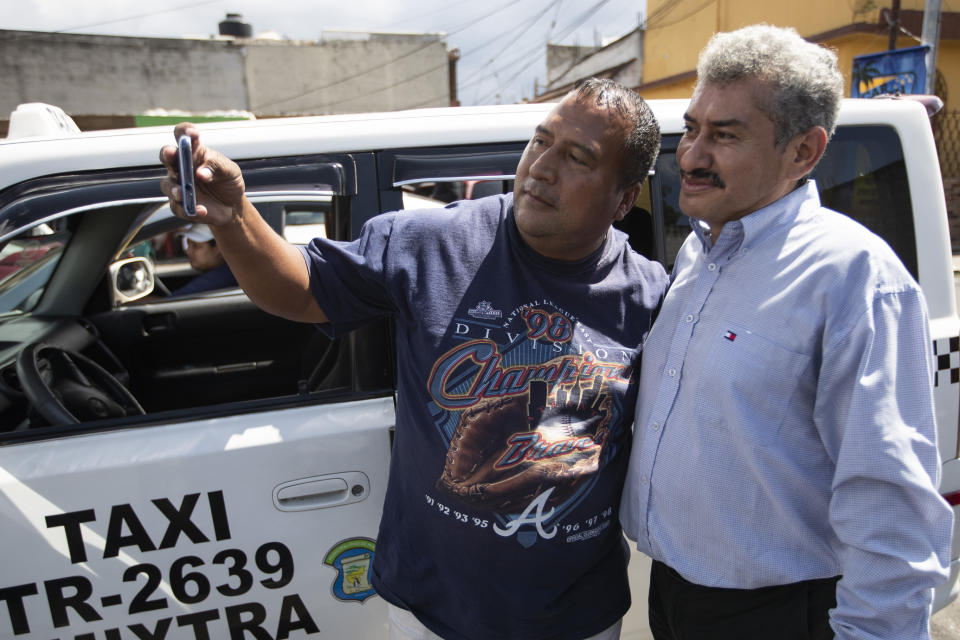 Un individuo se saca un selfie con Fabio Rodolfo Vásquez (der) en la Ciudad de Guatemala el 19 de septiembre del 2020. Un video que hizo Vásquez bailando son su esposa se hizo viral. (AP Photo/Moisés Castillo)