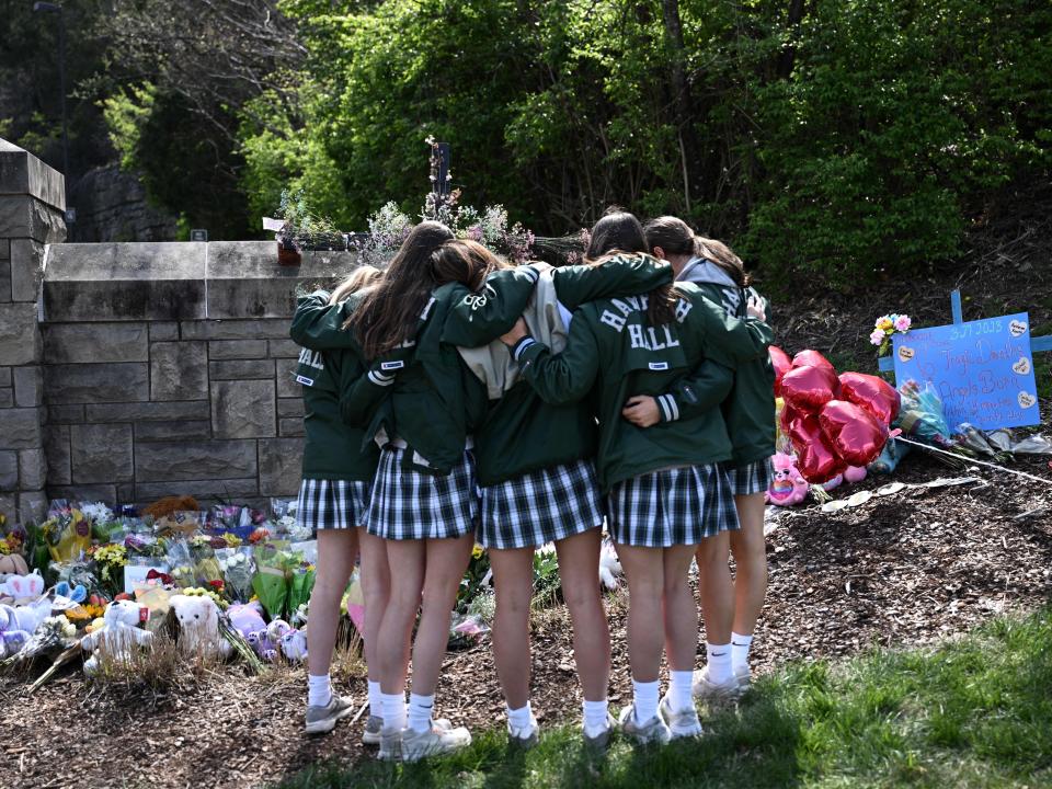 Girls embrace in front of a makeshift memorial for victims by the Covenant School building at the Covenant Presbyterian Church following a shooting, in Nashville, Tennessee