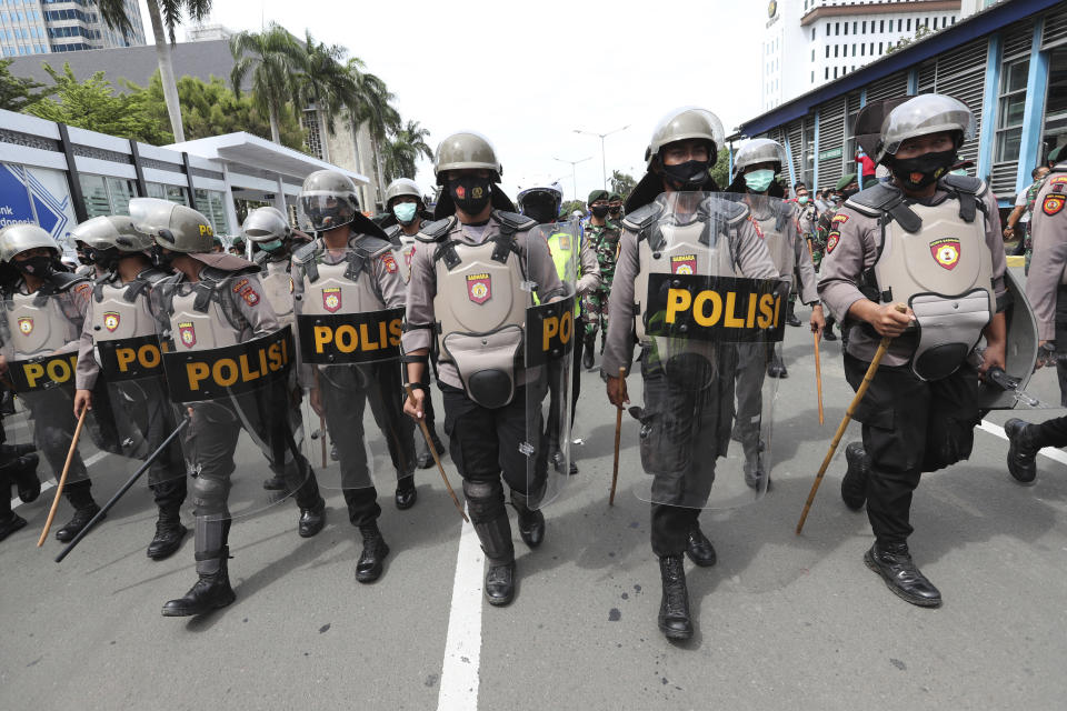 Police officers in riot gear move to push back supporters of Rizieq Shihab, leader of the Islam Defenders Front, during a rally in Jakarta, Indonesia, Friday, Dec. 18, 2020. Hundreds of protesters marched in Indonesia's capital on Friday to demand the release of the firebrand cleric who is in police custody on accusation of inciting people to breach pandemic restrictions and ignoring measures to curb the spread of COVID-19 by holding several events, and justice for his six followers who were killed in a shootout with the police. (AP Photo/Tatan Syuflana)