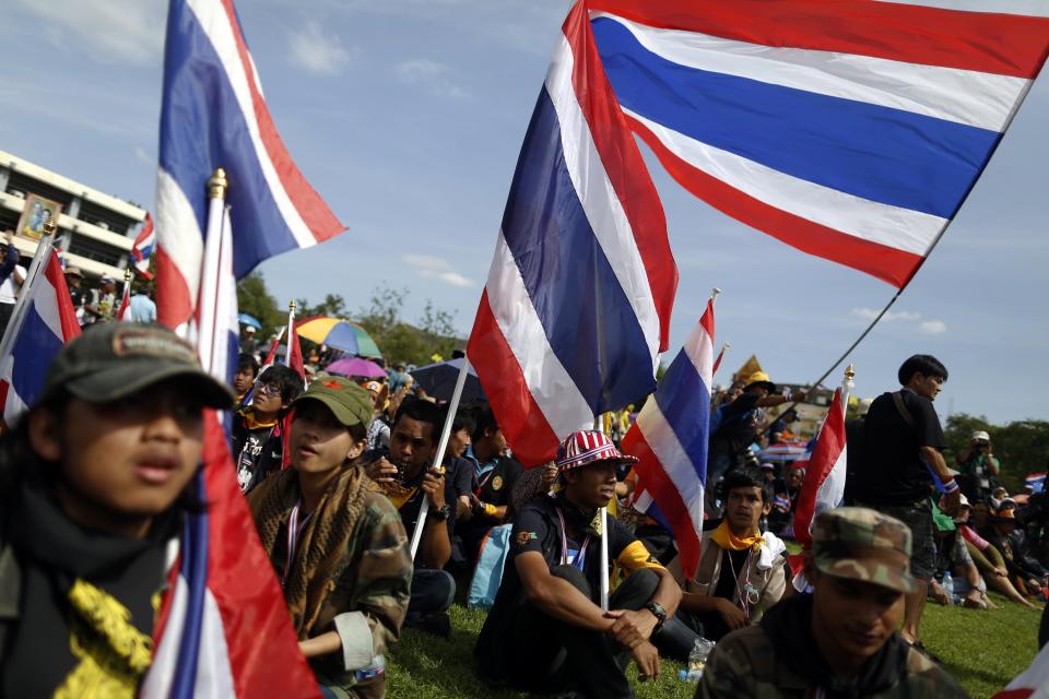 Anti-government protesters hold national flags after breaking into the compound of the Royal Thai Army headquarters in Bangkok