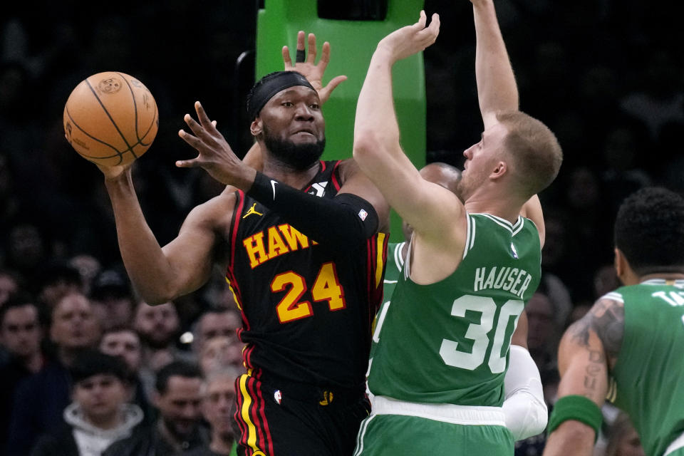 Atlanta Hawks forward Bruno Fernando (24) looks to pass the ball while pressured by Boston Celtics forward Sam Hauser (30) during the first half of an NBA basketball game Wednesday, Feb. 7, 2024, in Boston. (AP Photo/Charles Krupa)