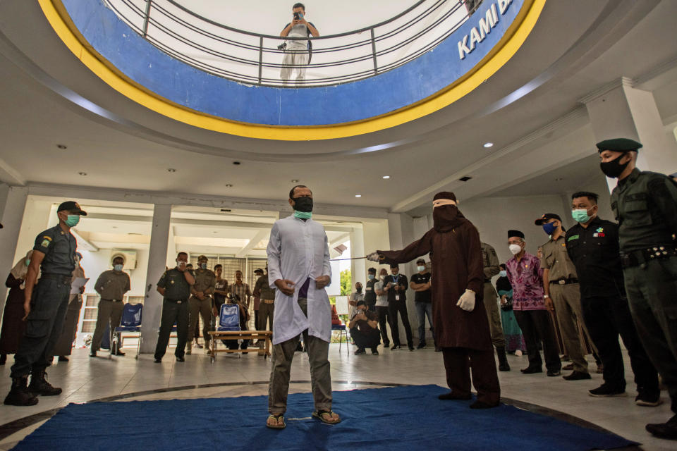 FILE - A Shariah Law official uses a rattan cane to whip one of two men convicted of gay sex in Banda Aceh, Aceh province, Indonesia, Thursday, Jan. 28, 2021. Two men in Indonesia's conservative Aceh province were caned 77 times each after neighbors reported them to the Shariah Police for having sex. (AP Photo/Riska Munawarah, File)