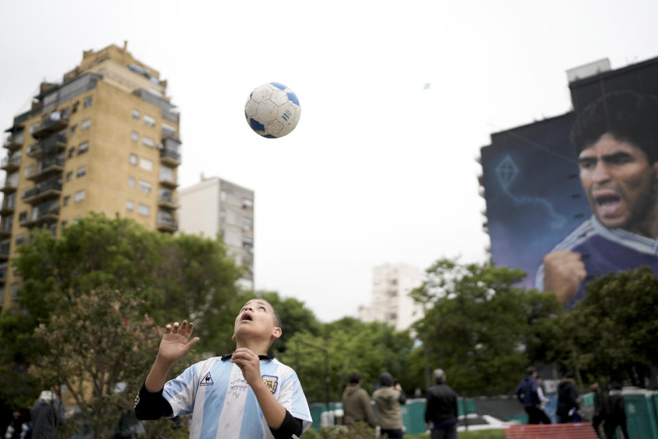 A child plays with a ball in front of a mural of Diego Maradona by artist Martin Ron in Buenos Aires, Argentina, Sunday, Oct. 30, 2022. Sunday marks the birth date of Maradona who died on Nov. 25, 2020 at the age of 60.(AP Photo/Rodrigo Abd)