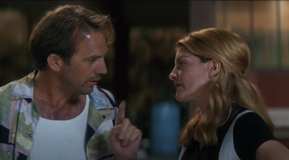 Actor Kevin Costner points at Rene Russo in the movie while they stand outside.