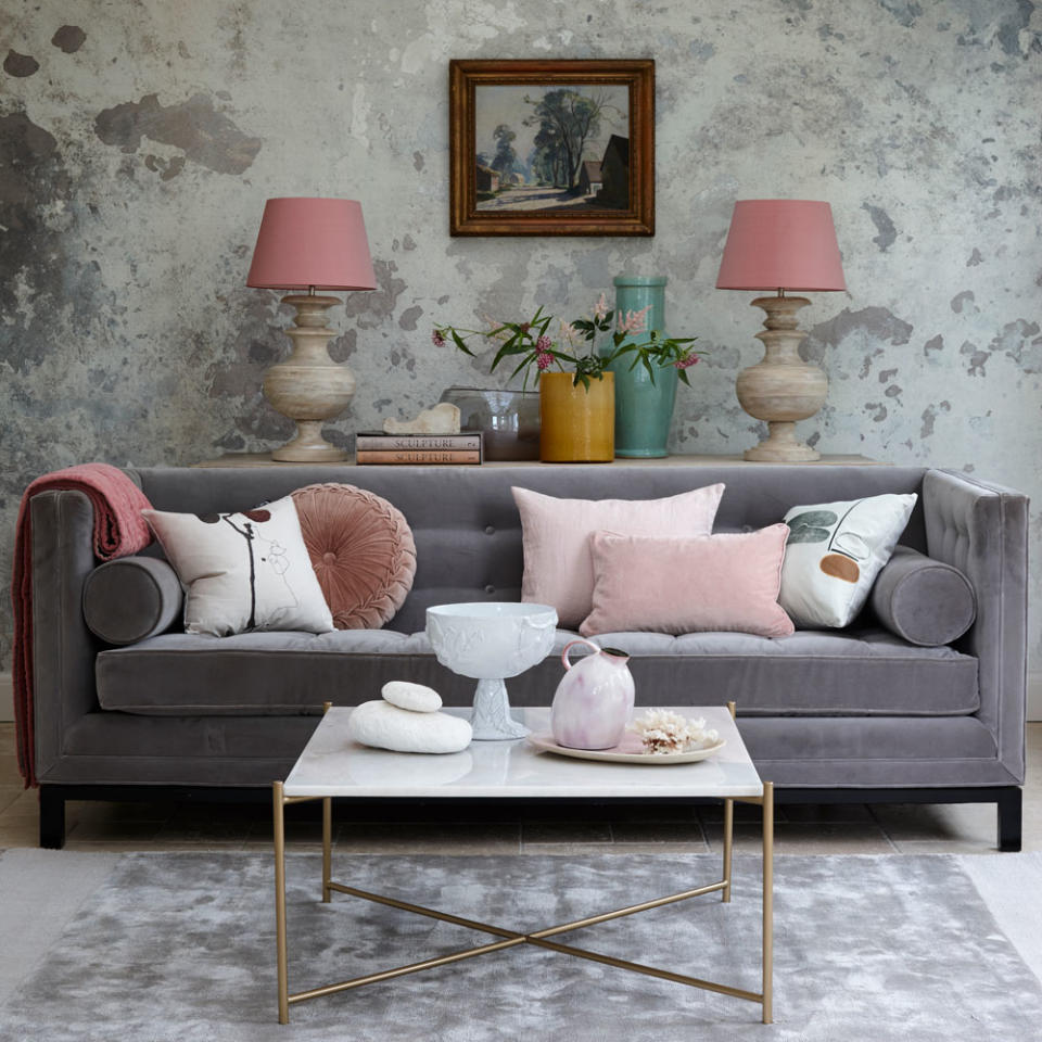<p> The striking rough-luxe wall mural brings texture and movement to the space. The metallic highlights of the silky silver rug and wallcovering reflect the light, giving this glam living room even more of a lift. </p> <p> A plush velvet sofa in a deeper grey punctuates the space and layers on the luxe. Combining touches of blush pink with the cool grey creates grown-up sophistication. </p>