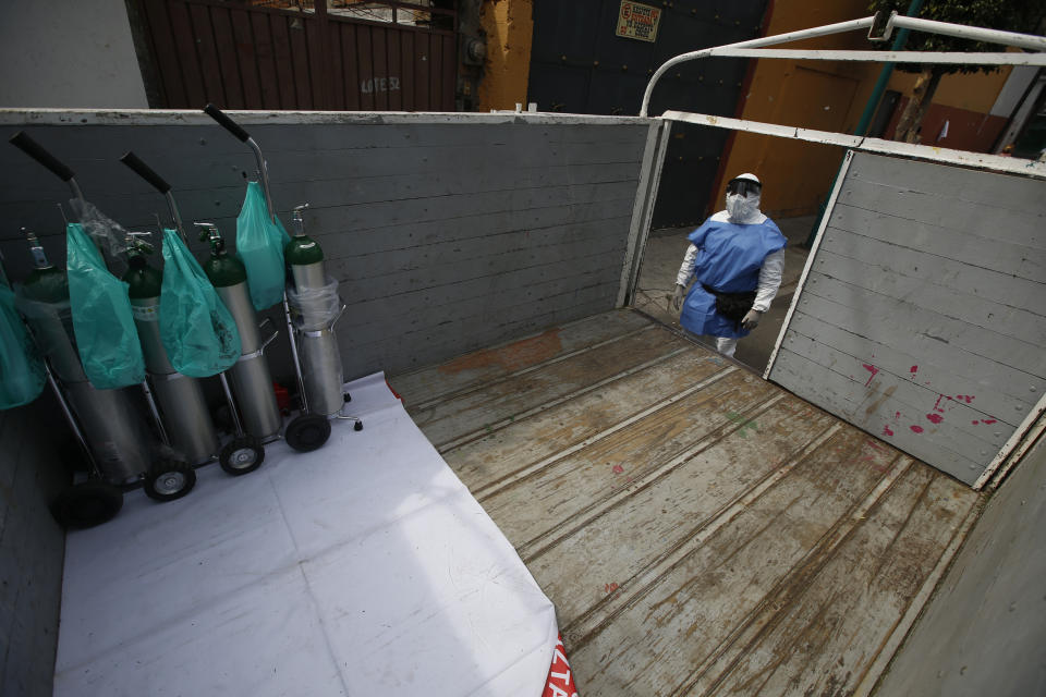 City worker Carlos Ruiz loads tanks of oxygen for COVID-19 patients, in the Iztapalapa borough of Mexico City, Friday, Jan. 15, 2021. The city offers free oxygen refills for COVID-19 patients. (AP Photo/Marco Ugarte)