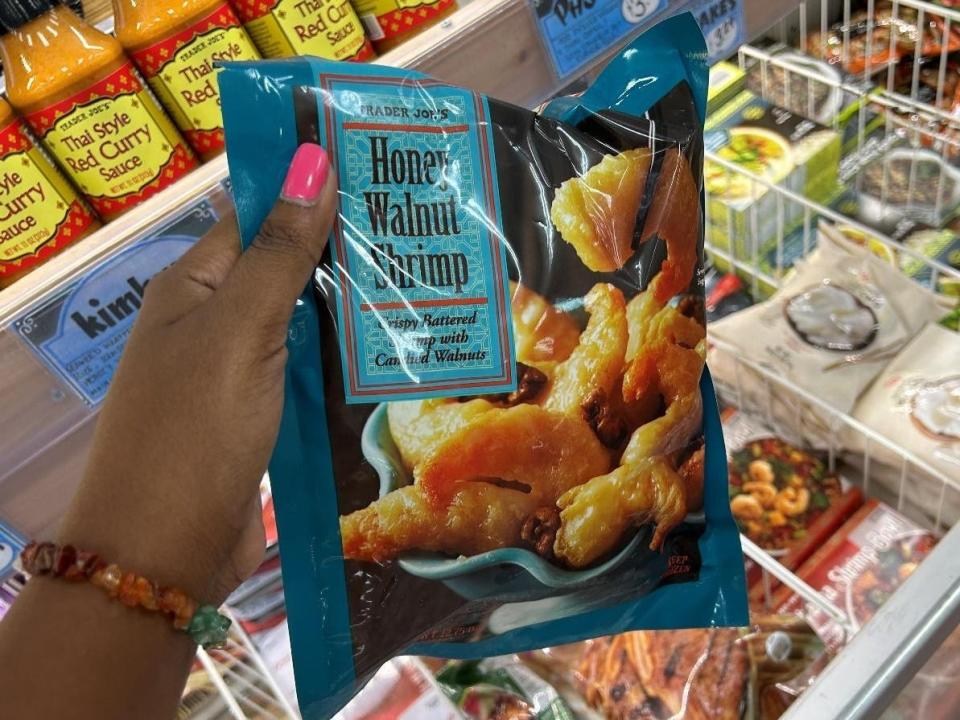 Woman holding a bag of honey-walnut shrimp from Trader Joe's.
