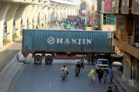 Motorcyclists pass through a gap in a barricade set up using shipping containers near the venue of a planned protest gathering organised by Awami Muslim League (AML), a political ally party of Imran Khan's Pakistan Tehreek-e-Insaf (PTI), in Rawalpindi, Pakistan, October 28, 2016. REUTERS/Faisal Mahmood