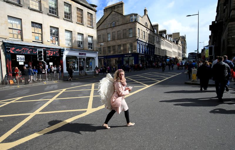 FILE PHOTO: A woman wearing angel wings crosses a road during the fringe festival in Edinburgh