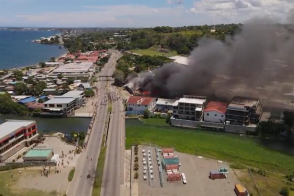Smoke rises from burning buildings during a protest in Honiara (AP)