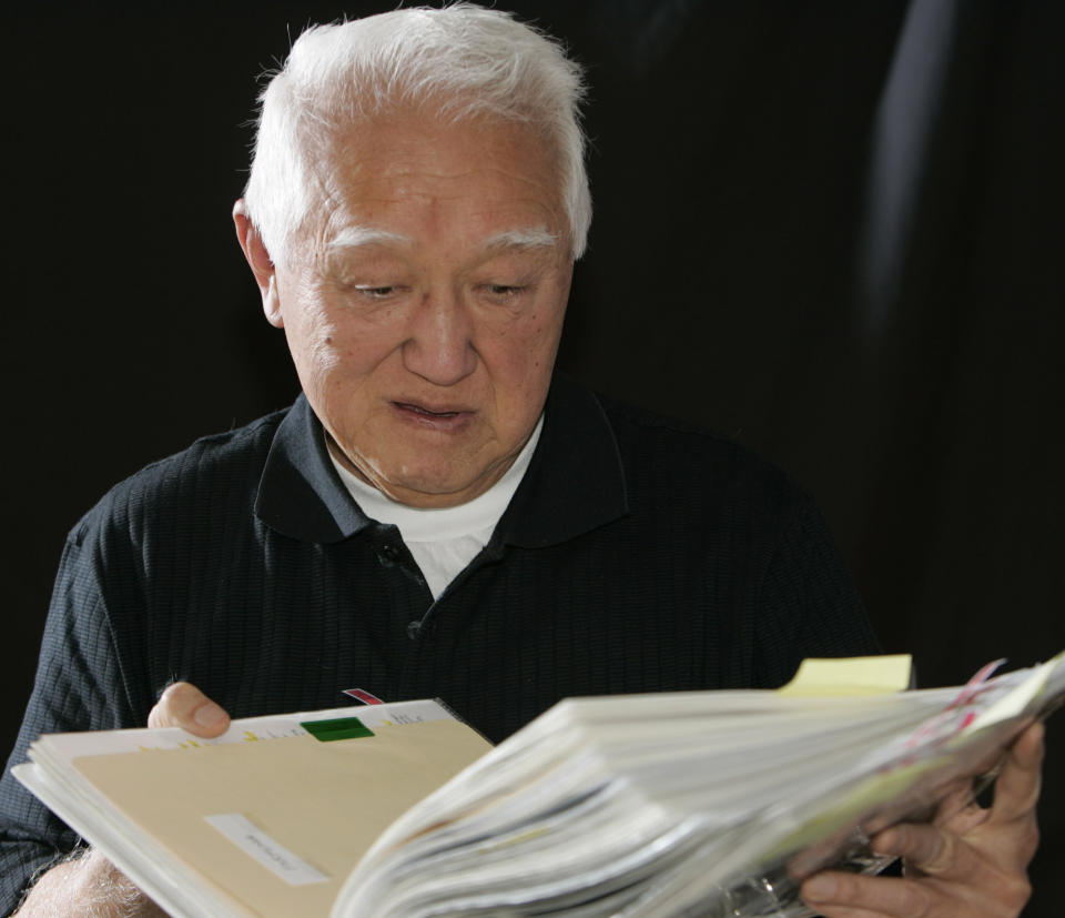 FILE - In this Nov. 16, 2007, file photo, Bob Fuchigami looks through one of the albums of photographs that he has collected on Camp Amache during an interview at his home near Evergreen, Colo. Fuchigami was 12-year-old when he and his family were forced to leave their 20-acre farm in Northern California for the Japanese-American internment camp in Granada, Colo. A University of Denver team is using a drone to create a 3D reconstruction of the camp in southern Colorado. The Amache effort is part of a growing movement to identify and preserve historical sites connected to people of color in the U.S. (AP Photo/Ed Andrieski, File)