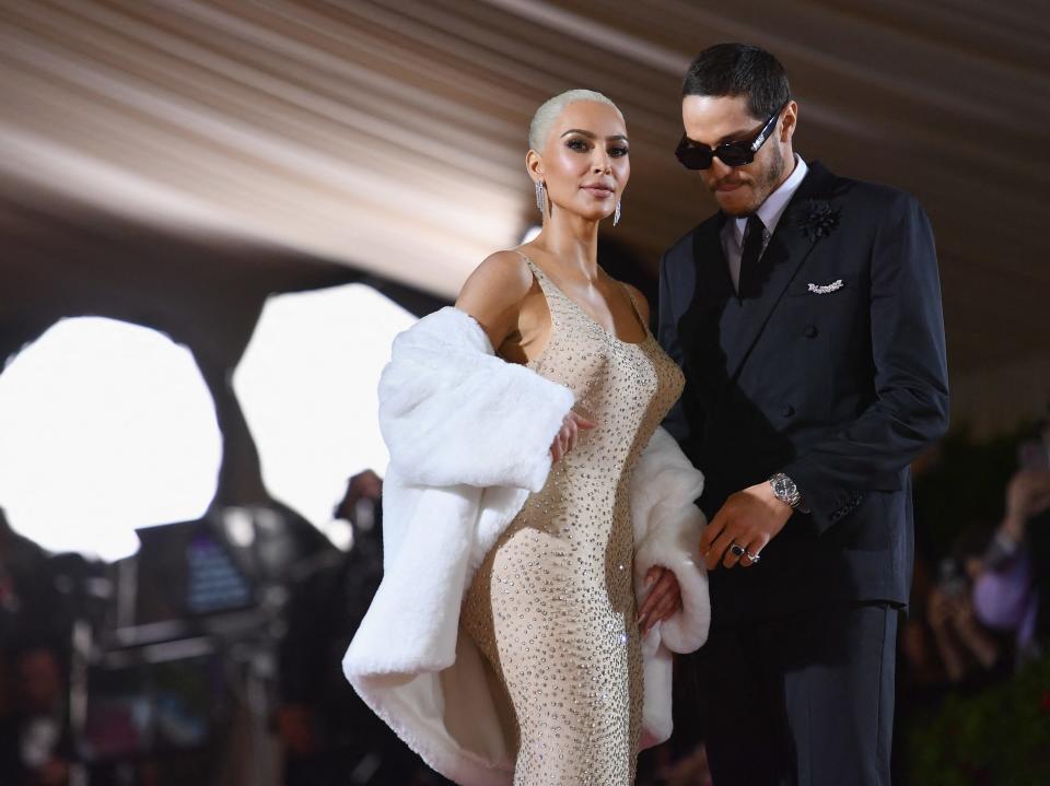 kim kardashian and pete davidson standing together at the met gala, with kardashian looking outwards and davidson looking slightly down at her, wearing sunglasses