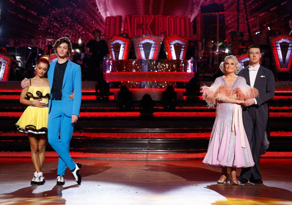 bobby, dianne, angela and kai stand under spotlight son ballroom floor in blackpool for strictly 2023