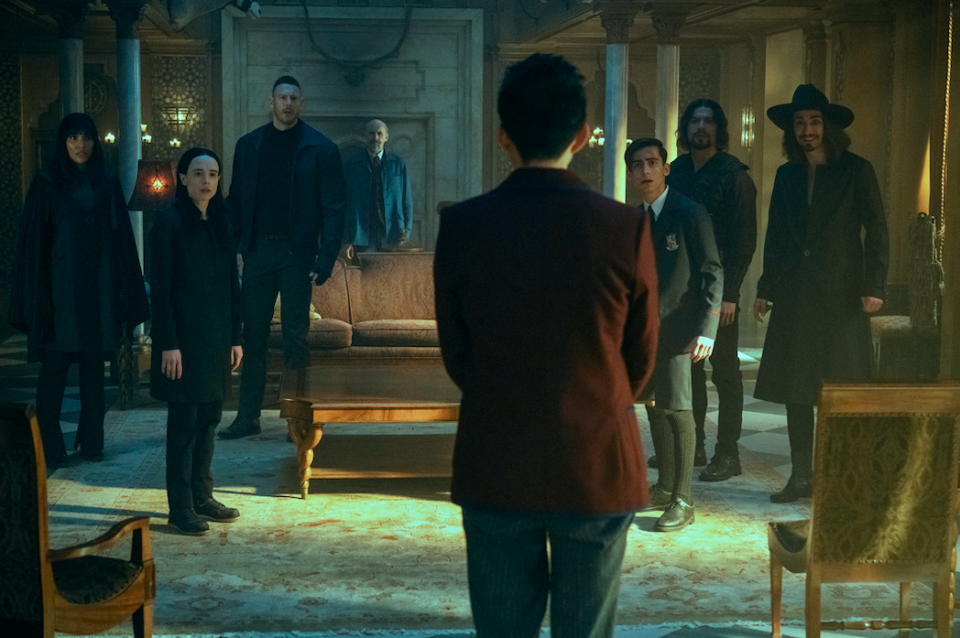 The Umbrella Academy all looking shocked at a man whose back is turned to the camera