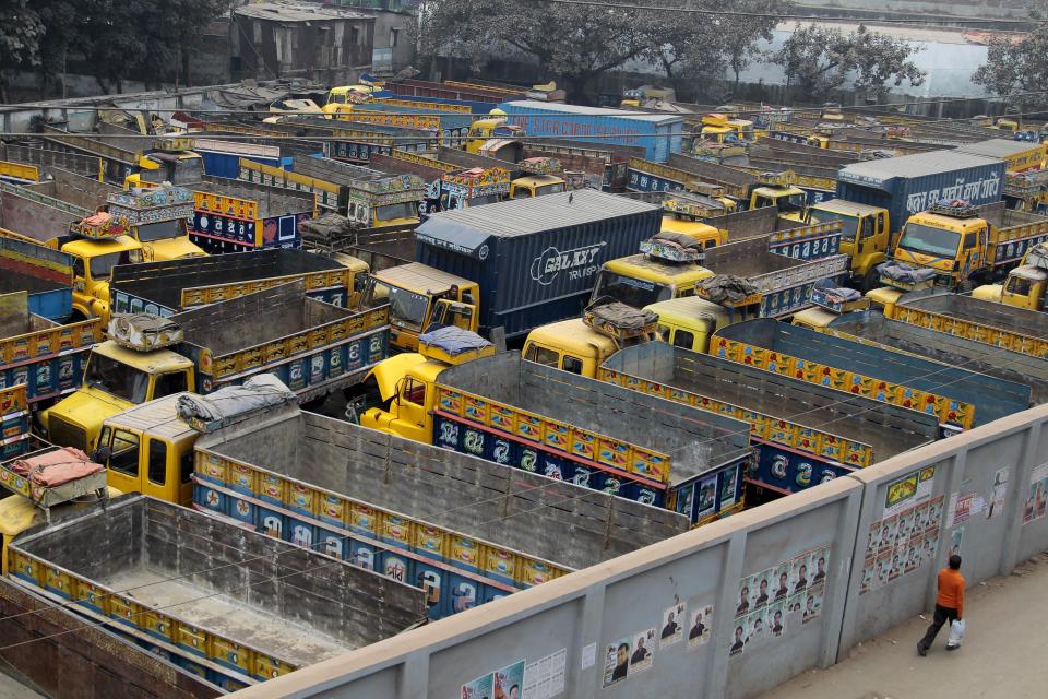 A man walks past commercial trucks parked at a station during a 48-hour nationwide strike called by the main opposition Bangladesh Nationalist Party (BNP) against Sunday's general election, in Dhaka, Bangladesh, Monday, Jan. 6, 2014. Bangladesh's ruling Awami League won one of the most violent elections in the country's history, marred by street fighting, low turnout and a boycott by the opposition that made the results a foregone conclusion. (AP Photo/A.M. Ahad)