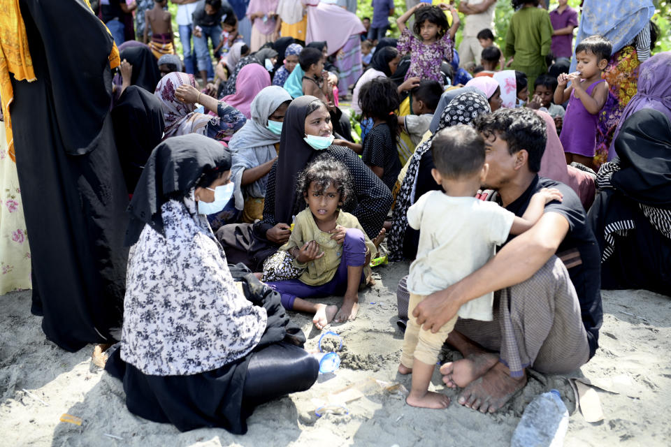 Ethnic Rohingya people sit on a beach after they land in Pidie, Aceh province, Indonesia, Sunday, Dec. 10, 2023. Two boats carrying hundreds of Rohingya Muslims, including women and children, arrived at Indonesia's northernmost province of Aceh on Sunday morning after being adrift for weeks. (AP Photo/Reza Saifullah)