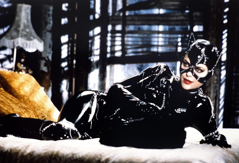 A woman in a catsuit lays out on a bed