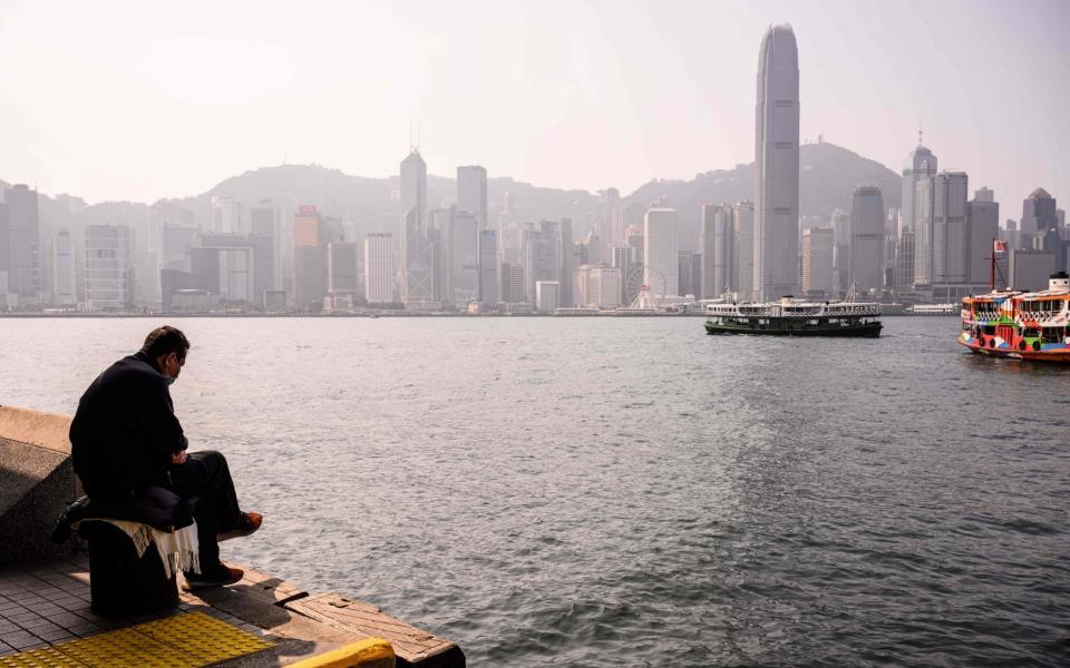 A man on the harbourside in Hong Kong - Anthony Wallace/AFP