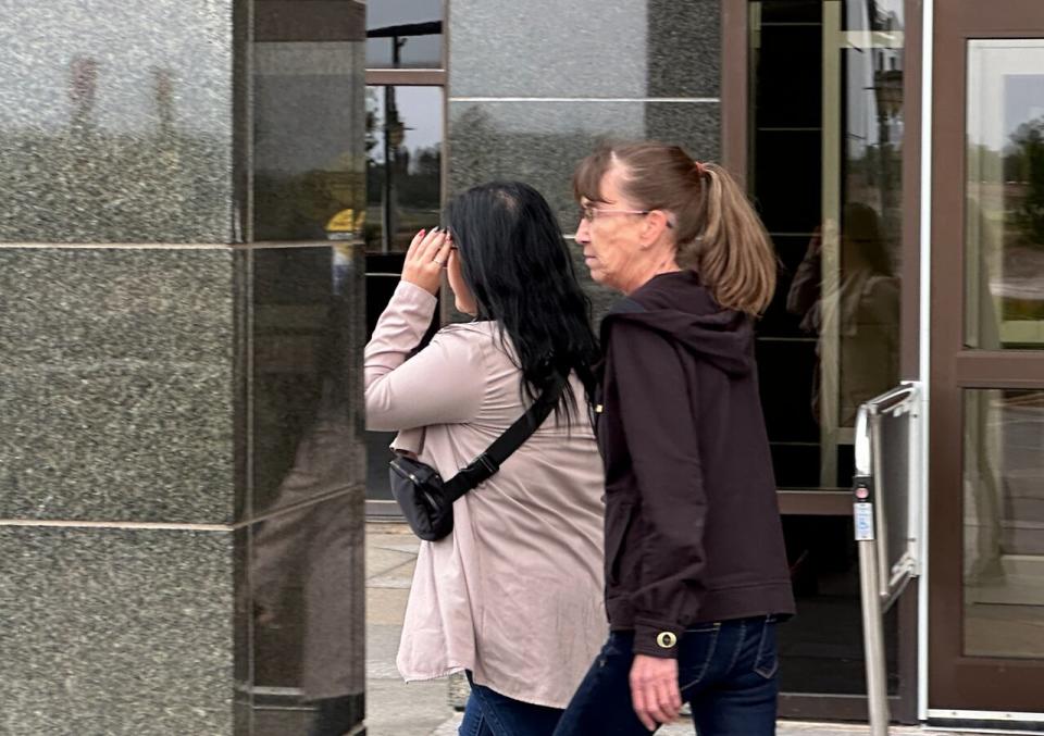 Bianca Chouinard, left, hides her faces from reporters as leaves the Moncton courthouse on Wednesday afternoon with a supporter after the sentencing hearing.  (Shane Magee/CBC - image credit)