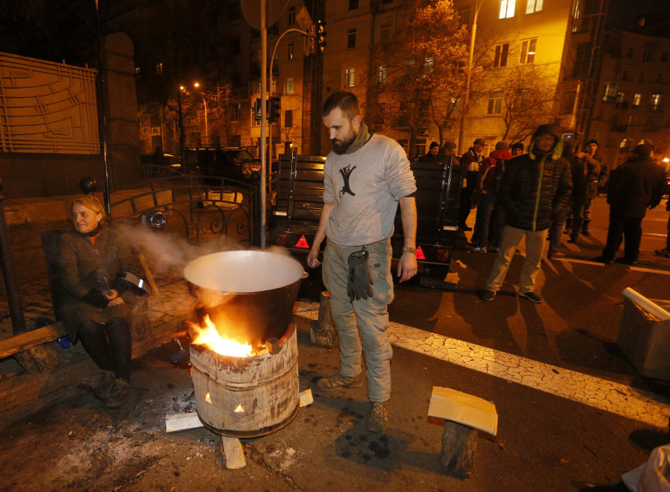 A activist cooks meals during a rally at the president's office in Kyiv, Ukraine, Monday, Dec. 9, 2019. A few hundreds of activists wait for the results of peace talks in Paris. Ukraine's President Volodymyr Zelenskiy will have his first face-to-face meeting with Russian President Vladimir Putin to end Moscow-backed conflict in Ukraine's east, which has killed over 14,000 people since 2014. (AP Photo/Efrem Lukatsky)