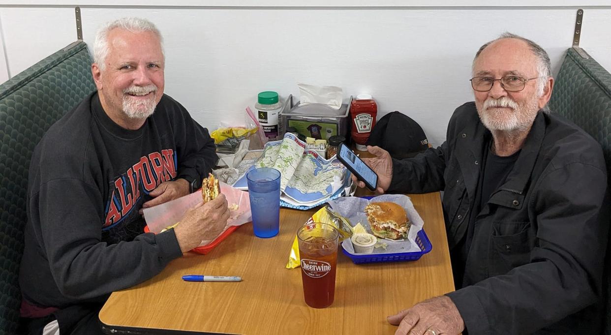 Mark Girdner (right) and Mike Adams, both of California, enjoy a meal during their roadtrip across America from California to North Carolina. Girdner misread the trail near Natural Dam, Arkansas, and drove off a 30-foot bluff into a flooded creek on May 1.