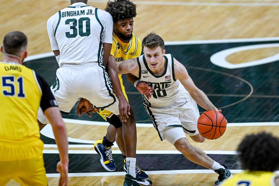 Michigan State's Jack Hoiberg, right, moves past Michigan's Mike Smith during the second half on Sunday, March 7, 2021, at the Breslin Center in East Lansing.