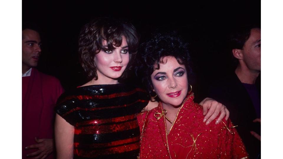 Maria Burton standing with Elizabeth Taylor in a red outfit