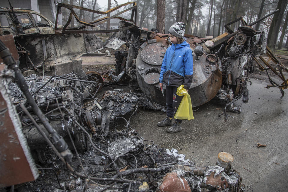 A boy looks at a destroyed Russian tank after recent battles in Bucha, close to Kyiv, Ukraine, Friday, Apr. 1, 2022. Talks to stop the fighting in Ukraine have resumed as another attempt to rescue civilians from the besieged port city of Mariupol broke down. Also, Russia is accusing the Ukrainians of launching a cross-border helicopter attack on a fuel depot. (AP Photo/Oleksandr Ratushniak)