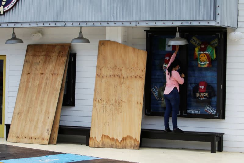 A woman stands next to plywood to board up a restaurant in preparation for the arrival of Hurricane Delta, in Cancun