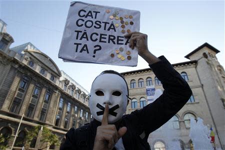 A protester gestures while holding up a placard, which reads: "How much does your silence cost?", during a rally in Bucharest, against plans to open Europe's biggest open-cast gold mine in Romania September 15, 2013. REUTERS/Bogdan Cristel