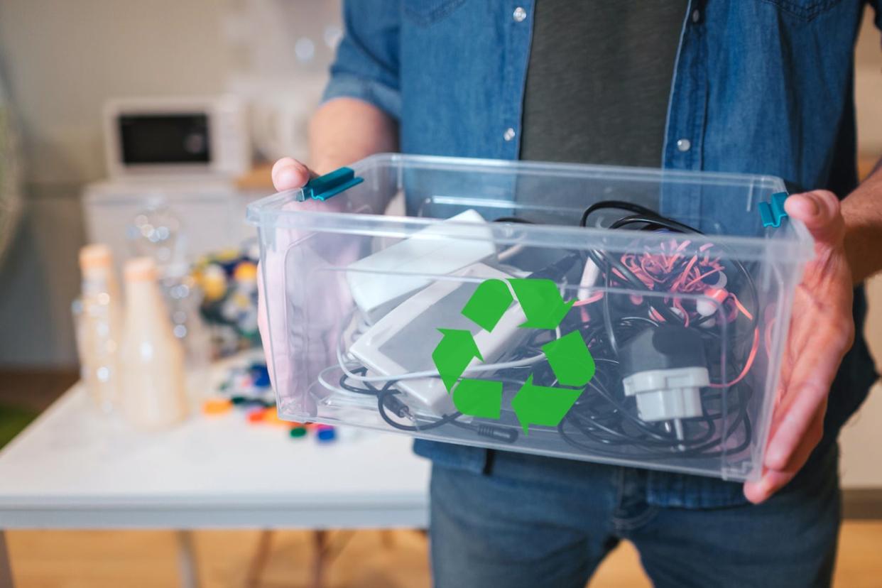 Recycling concept. An electronic waste in recycling contaner close-up. Responsible man is protecting environment while sorting the waste at home