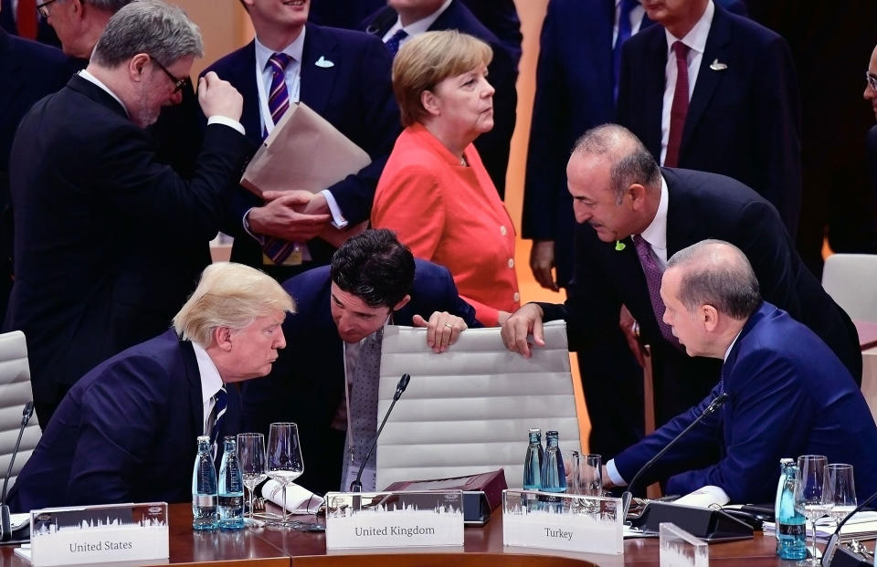 <p>President Donald Trump (L) talks to the President of Turkey Recep Tayyip Erdogan (R) while German Chancellor Angela Merkel is seen in the background before the beginning of first working session of the G20 Nations Summit with the topic ‘Global Growth and Trade’ on July 7, 2017 in Hamburg, Germany. (Photo: Thomas Lohnes/Getty Images) </p>