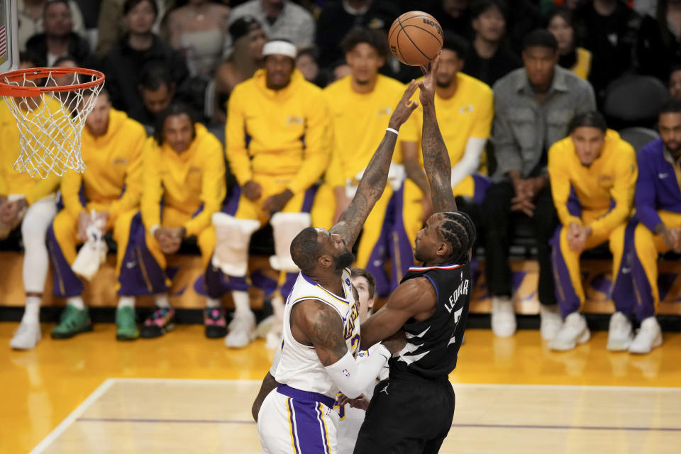 Los Angeles Clippers forward Kawhi Leonard, center right, shoots over Los Angeles Lakers forward LeBron James, center left, during the first half of an NBA basketball game in Los Angeles, Sunday, Jan. 7, 2024. (AP Photo/Eric Thayer)
