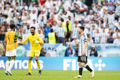 Lionel Messi of Argentina walks off the pitch as Mohammed Al-Owais of Saudi Arabia celebrates at full time during the FIFA World Cup