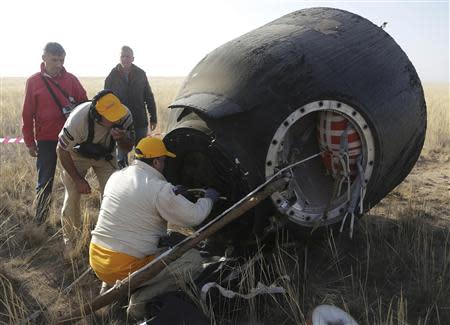 Russia's space agency ground specialists open the door of the Soyuz TMA-08M space capsule shortly after it landed some 146 km southeast of tthe town of Zhezkazgan, Kazakhstan, September 11, 2013. REUTERS/Maxim Shipenkov/Pool