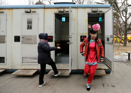 A male folk artist (R) dressed as a traditional Chinese woman walks out of a mobile toilet ahead of a performance at a Spring Festival Temple Fair on the fifth day of the Chinese Lunar New Year at Longtan Park in Beijing, China February 14, 2013. REUTERS/Jason Lee/File Photo